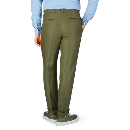 A person standing in Boglioli green washed Irish linen trousers and gray sneakers paired with a light blue shirt.
