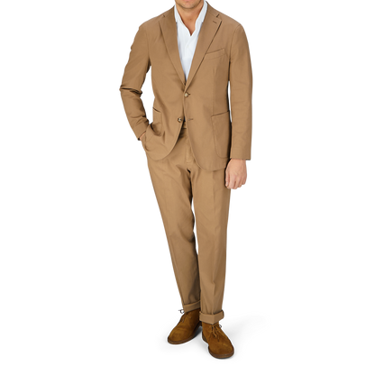 A man wearing a tan Boglioli Tobacco Brown Washed Cotton K Jacket and brown shoes stands against a light-colored background.