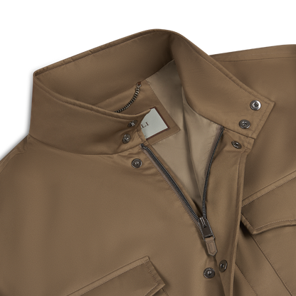 Close-up of Canali’s Rust Brown Nylon Four Pocket Field Coat with a high collar, partially unzipped to reveal a beige lining and chain loop. Snap buttons, flap pockets, and a white label inside the collar complete the look. , available at Richard Gelding Mayfair