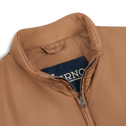 A close-up of the Herno Camel Brown Lightweight Nylon Gilet with a stand-up collar and visible silver zipper, partially unzipped, showing a navy Herno label inside against a plain white background—a stylish outerwear piece. , available at Richard Gelding Mayfair