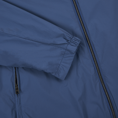 A close-up of the Herno Blue Lightweight Nylon Zip Jacket shows its smooth fabric, long sleeve with elastic cuff, and a visible black vertical zipper along the right side, emphasizing its practical design and construction. , available at Richard Gelding Mayfair