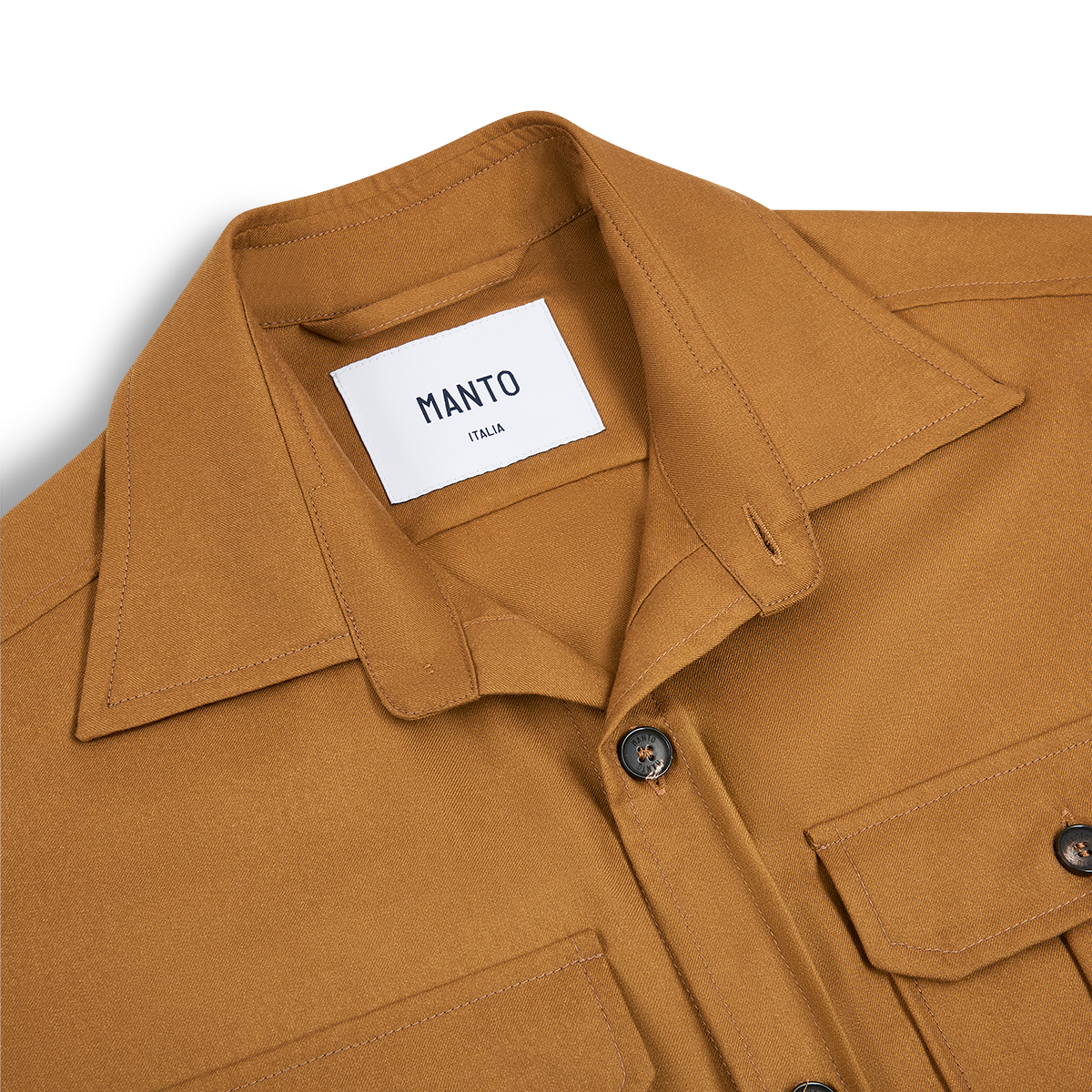 A close-up of the Manto Camel Wool/Silk Gubbio Overshirt shows a brown collared shirt with two front flap pockets and dark buttons. The thick, structured fabric blends premium wool and silk, reflecting quality materials and craftsmanship. , available at Richard Gelding Mayfair