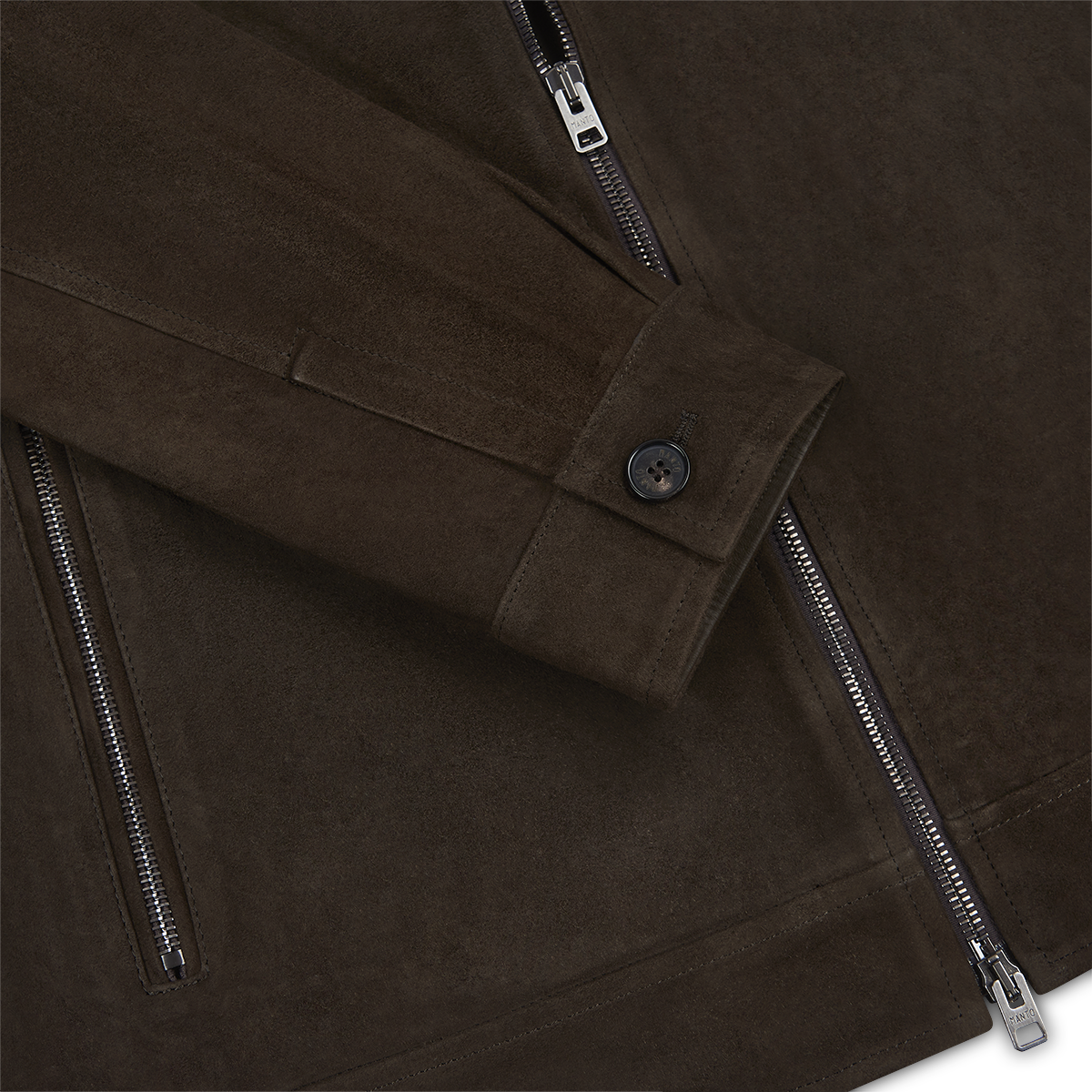 Close-up of the Manto Chocolate Brown Strozzi Zip Suede Blouson, featuring a sleeve with a black buttoned cuff and two silver zippers. The suede’s texture and refined stitching showcase this men’s jacket’s craftsmanship. , available at Richard Gelding Mayfair