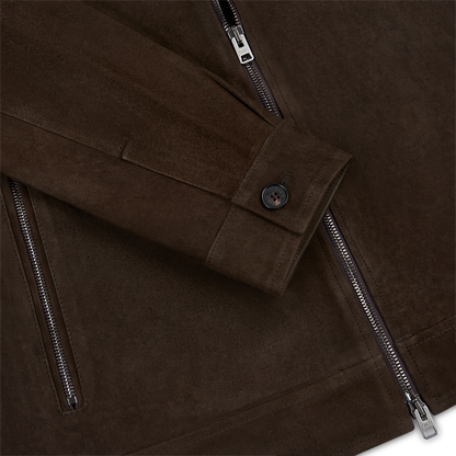 Close-up of the Manto Chocolate Brown Strozzi Zip Suede Blouson, featuring a sleeve with a black buttoned cuff and two silver zippers. The suede’s texture and refined stitching showcase this men’s jacket’s craftsmanship. , available at Richard Gelding Mayfair