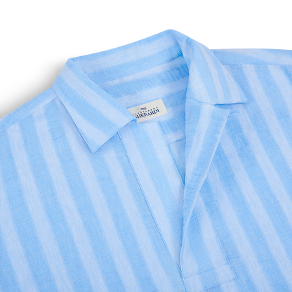 Close-up of the Alessandro Gherardi Blue Stripe Cotton/Linen Popover Camp Collar Shirt, featuring a single breast pocket and an inner collar label. The lightweight shirt is partially folded, showcasing its camp collar design. , available at Richard Gelding Mayfair