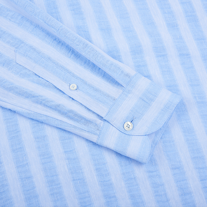 A close-up of the Alessandro Gherardi Blue Stripe Cotton/Linen Popover Camp Collar Shirt shows its neatly pressed cuff and sleeve placket with two white buttons, highlighting the fabric’s subtle textured pattern. , available at Richard Gelding Mayfair