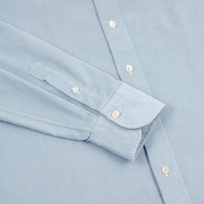 The Sky Blue Cotton Corduroy Shirt by Alessandro Gherardi, crafted from fine Italian fabric, is displayed flat with one sleeve folded, featuring white buttons and a pointed cuff for a crisp, tailored look and elegant design. , available at Richard Gelding Mayfair