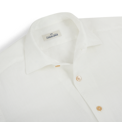 A close-up of the Alessandro Gherardi White Linen Long Sleeve Shirt made of lightweight fabric, featuring tan buttons and the brand label inside the collar, neatly displayed on a white background. , available at Richard Gelding Mayfair