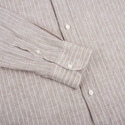 A close-up of the Alessandro Gherardi Brown Stripe Linen Mandarin Collar Shirt highlights the torso and one long sleeve, featuring white buttons on the cuff and placket. The textured linen fabric and vertical stripes enhance its relaxed, stylish look. , available at Richard Gelding Mayfair
