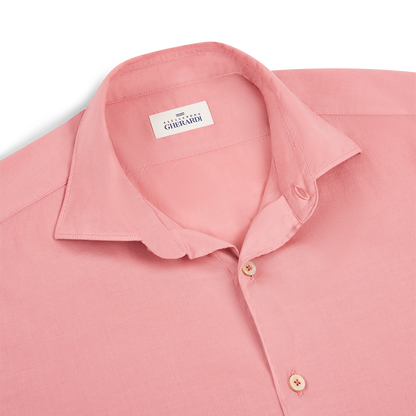 A neatly folded Pink Muslin Cotton Blend Beach Shirt by Alessandro Gherardi features a classic collar, light buttons, and a white label with the brand name inside. The breathable fabric looks soft and smooth, ideal for summer wear. , available at Richard Gelding Mayfair