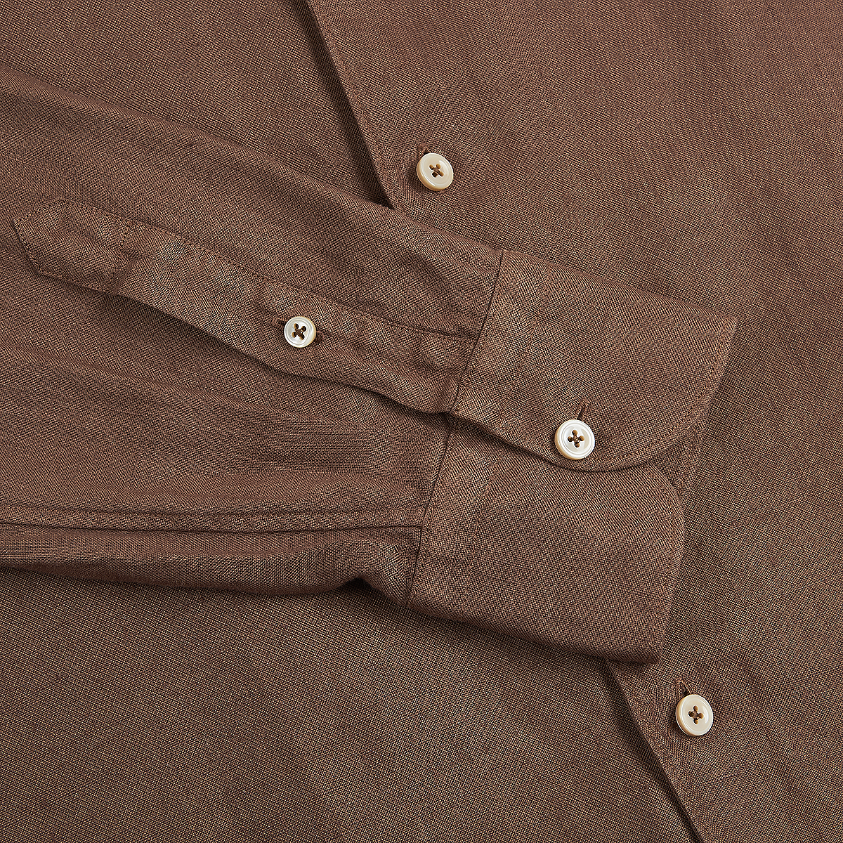 A close-up of the Alessandro Gherardi Tobacco Brown Linen One Piece Collar Casual Shirt shows textured fabric, visible stitching, and two beige buttons on the cuff with another on the placket. , available at Richard Gelding Mayfair
