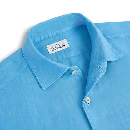 A close-up of the Alessandro Gherardi Mid Blue Linen One Piece Collar Casual Shirt, featuring a soft, textured fabric, cream buttons, and a brand label sewn inside the collar. The shirt is neatly laid flat. , available at Richard Gelding Mayfair
