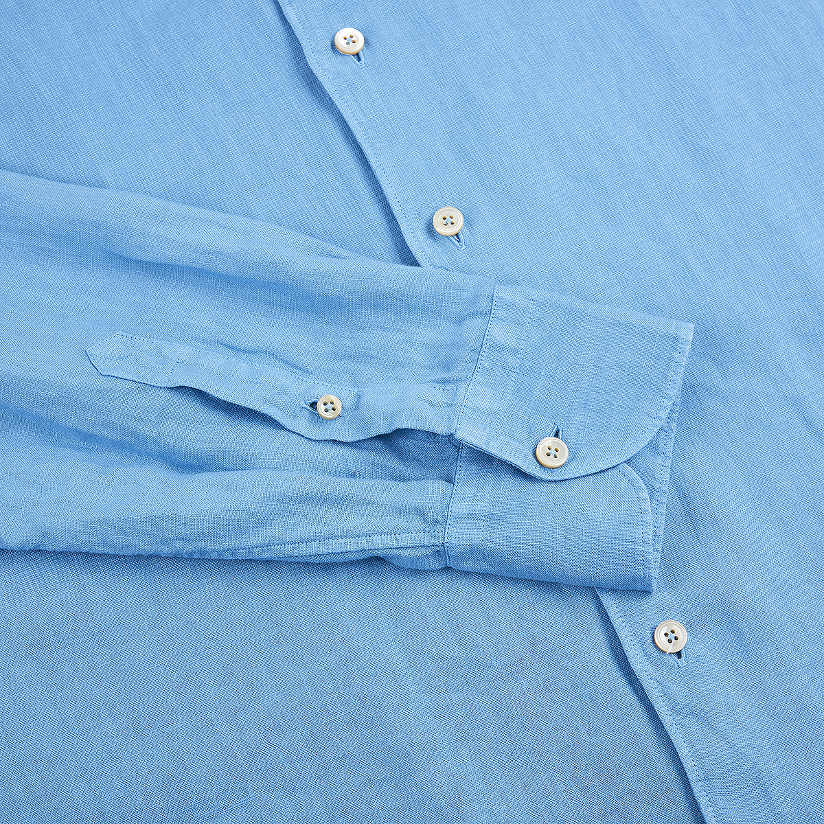 A close-up of the Alessandro Gherardi Mid Blue Linen One Piece Collar Casual Shirt laid flat, showing the buttoned cuff, front with white buttons, and soft textured linen fabric neatly arranged for display. , available at Richard Gelding Mayfair