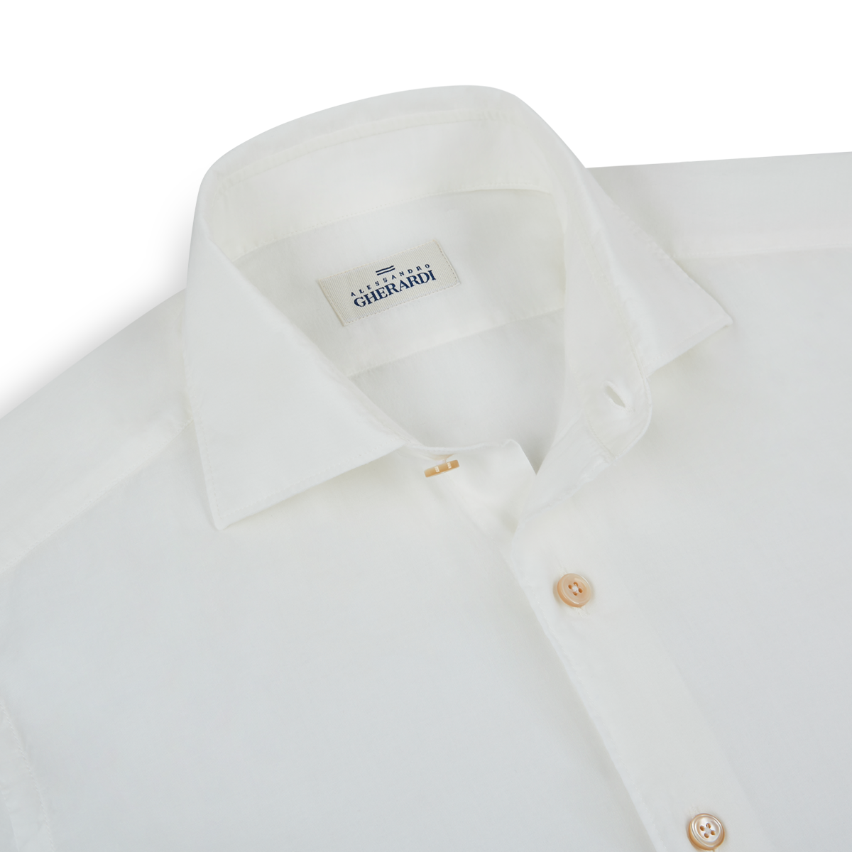 A close-up of a neatly folded Alessandro Gherardi White Muslin Beach Shirt shows its classic collar, light brown buttons, and inner label against a plain white background. , available at Richard Gelding Mayfair