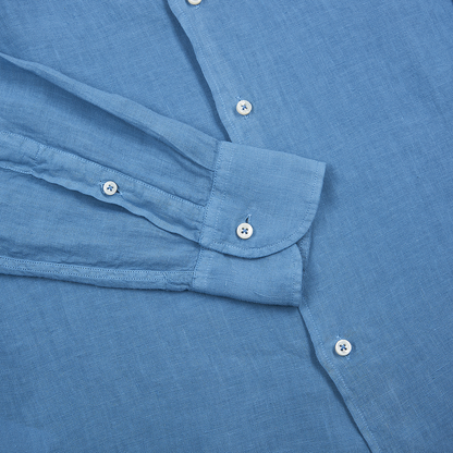 A close-up of the Fedeli Blue Linen Cutaway Collar Nick ML Shirt, featuring long sleeves, white buttons, a folded cuff with two buttons, and soft textured linen fabric neatly displayed on a flat surface. , available at Richard Gelding Mayfair