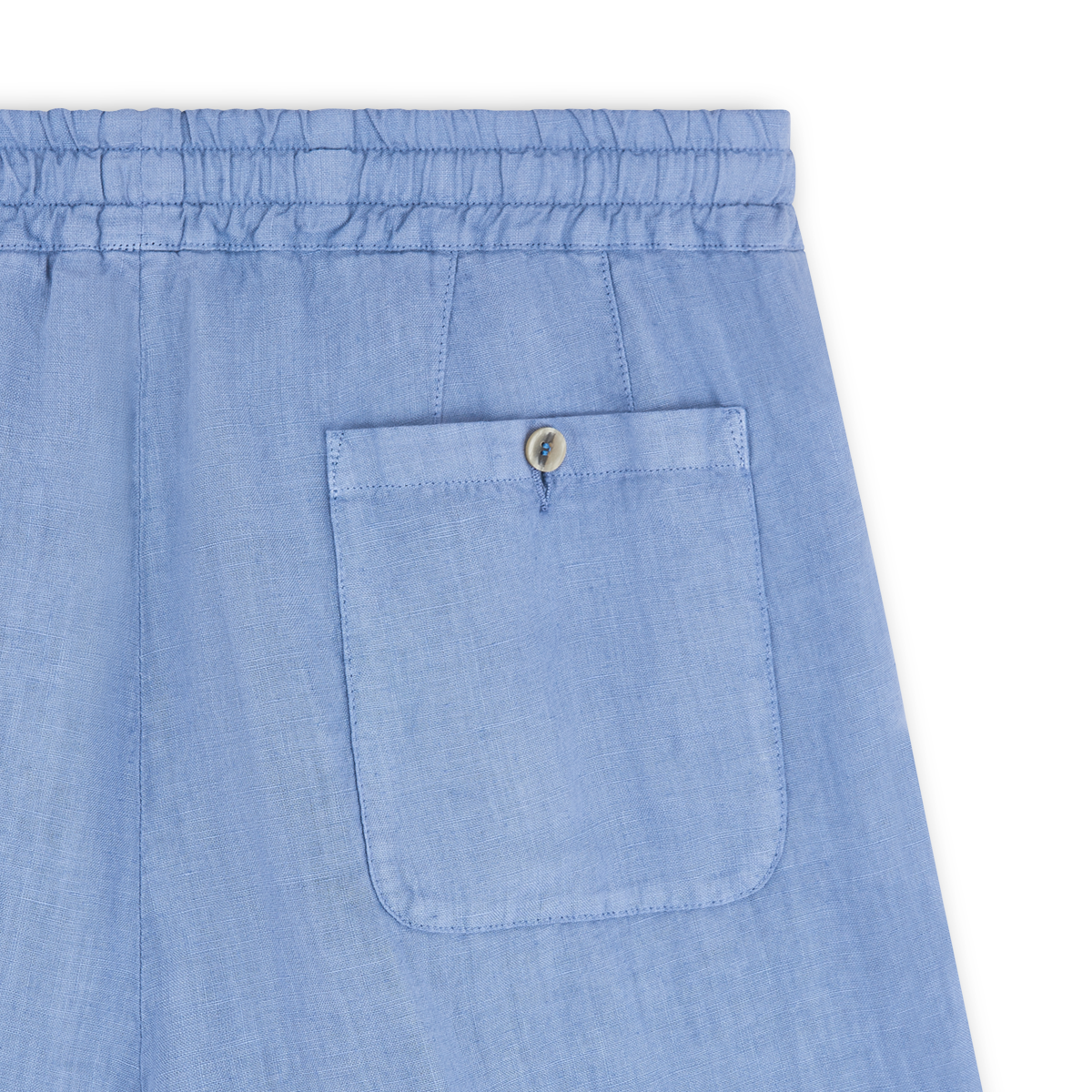 Close-up of Altea’s Sugar Packet Blue Linen Drawstring Trouser featuring a lightweight elastic waistband and a single back pocket with a flap and tan button. Visible stitching details stand out against the white background. , available at Richard Gelding Mayfair