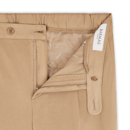 Close-up of Beige Cotton/Silk Stretch Waistband Chinos by Barmas featuring an open zipper, button closure, elastic back waistband, inner lining with repeating Barmas logo, and a white Barmas label sewn inside. , available at Richard Gelding Mayfair