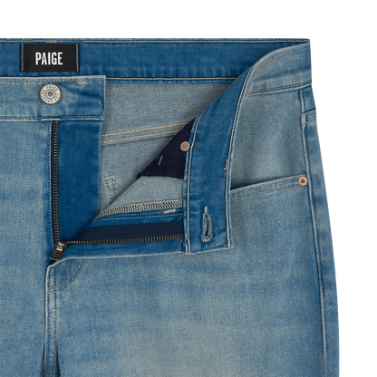 Close-up of Paige Ferdinand Blue Cotton Transcend Normandie Straight Leg Jeans with waistband, zipper, and button fly partially open. Features a black PAIGE label inside the waistband, copper rivets at pockets, and a casual faded wash. , available at Richard Gelding Mayfair