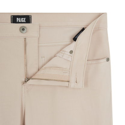 Close-up of Seashell Ecru Cotton Transcend Normandie Straight Leg Jeans by Paige, showing the open waistband and fly with a metal zipper, visible stitching, metallic button and rivets, and a black PAIGE label inside. , available at Richard Gelding Mayfair