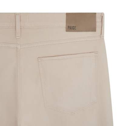 Close-up of the back of Seashell Ecru Cotton Transcend Normandie Straight Leg Jeans by Paige, featuring a single back pocket, visible stitching, and a tan leather waistband patch embossed with the brand name. , available at Richard Gelding Mayfair