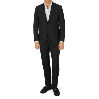 A man is posing in a Canali Black Virgin Wool Twill Suit.