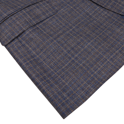 Close-up of a blue and brown Canali Gingham checked fabric of a tailored suit jacket laid flat against a white background.