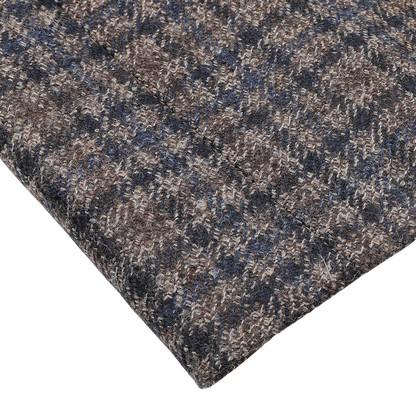 Close-up of a section of textured fabric with a houndstooth pattern in brown, gray, and blue tones, resembling the classic style of the Brown Gunclub Check Wool Drop 6 Blazer by Canali, displayed on a white surface.