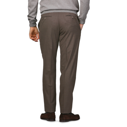 A person wearing a gray sweater and Canali's Brown Matte Wool Flat Front Trousers is standing with their back facing the camera.