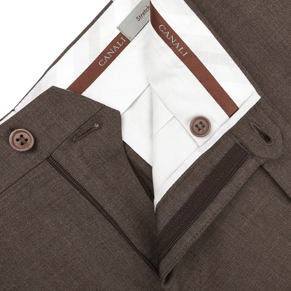 Close-up of tailored Canali Brown Matte Wool Flat Front Trousers, featuring zipper and black button detail, highlighting the interior label and meticulous stitching.
