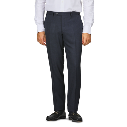 A person in a white shirt, Canali Dark Blue Melange Wool Flat Front Trousers with customizable length, and black loafers stands against a plain background.