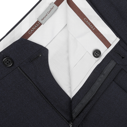 Close-up of a pair of dark blue melange, tailored fit trousers with a partially open front zipper and button, subtly revealing a white lining and Canali brand labels.