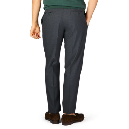 A person standing with their back toward the camera, wearing tailored formal Canali trousers in dark grey tropical wool and brown shoes.