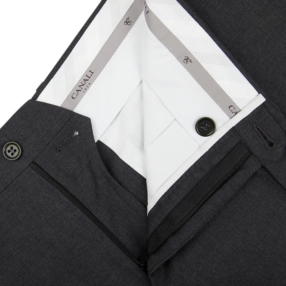 Close-up view of a men's dark suit jacket with a patterned lining and Canali dark grey tropical wool flat front trousers detail.