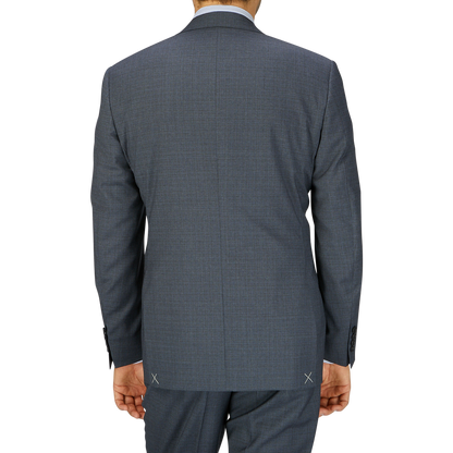 Rear view of a man wearing a full canvas construction Canali Grey-Blue Melange Wool Suit jacket and pants, standing against a light grey background.