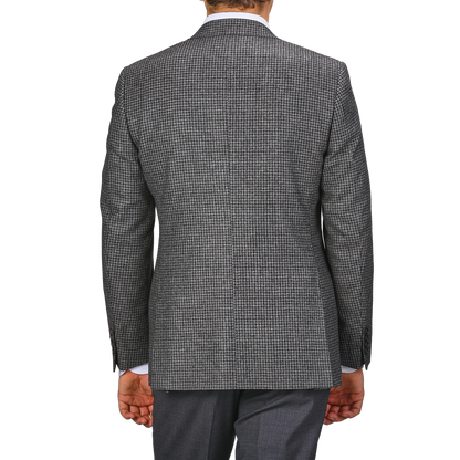 A person clad in the Grey Dogtooth Wool Drop 6 Blazer from Canali and matching gray pants, tailored from pure wool, is captured from the back with their arms hanging by their sides.