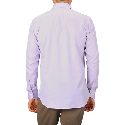 A man wearing a Canali Lilac Cotton Herringbone Single Cuff Shirt and brown pants stands with his back facing the camera.