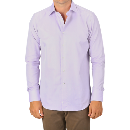 A man wearing a Canali Lilac Cotton Herringbone Single Cuff Shirt and brown pants stands facing forward, with only part of his face visible.