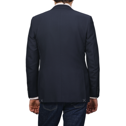 Rear view of a person in a Canali Navy Blue Hopsack Wool Blazer paired with jeans against a gray background.