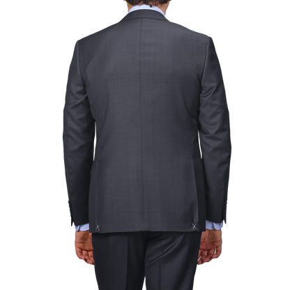 A man in a Canali Navy Blue Micro Design Wool Suit, paired with a light blue shirt, exudes classic sartorial elegance as he's photographed from the back against a neutral background.