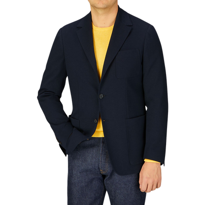 Man wearing a Canali navy cotton jersey unconstructed blazer over a yellow shirt paired with blue jeans.
