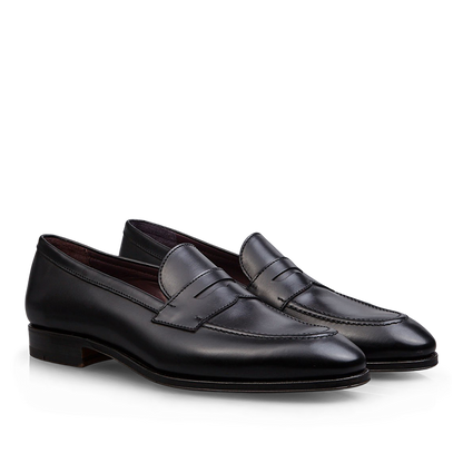 A pair of Carmina Black Calf Leather Uetam Penny Loafers with durable construction against a dark background.