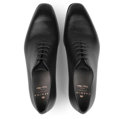 A pair of Carmina's Black Calf Leather Wholecut Rain Oxford Shoes, viewed from above, featuring a polished finish and laces that showcase the elegance of Goodyear welted construction.