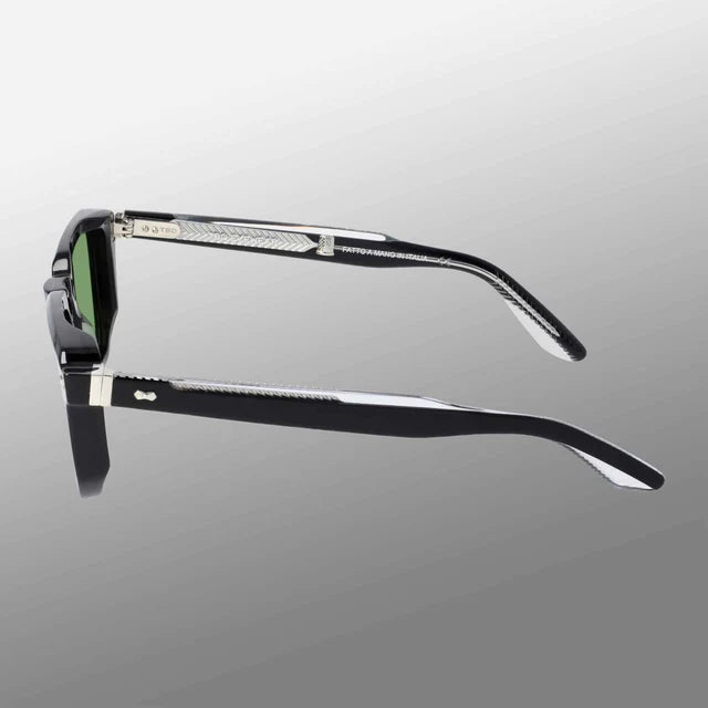 The Dart Black | Green sunglasses by TBD Eyewear feature thick black sustainable acetate frames, green mineral glass lenses, and textured silver details at the hinges, with handcrafted Italian quality shown against a gray gradient background. , available at Richard Gelding Mayfair