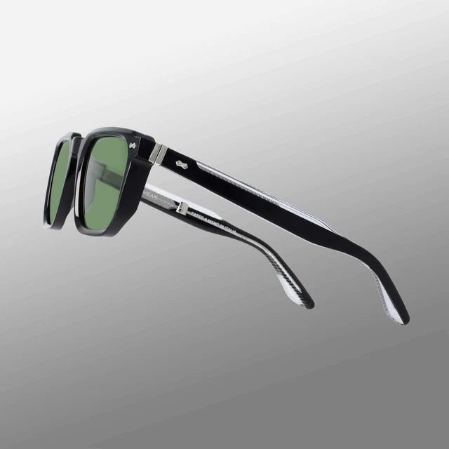 The Dart Black | Green sunglasses by TBD Eyewear feature sustainable black acetate frames, green-tinted rectangular lenses, and thick curved arms with metallic hinges, shown against a gradient grey background. , available at Richard Gelding Mayfair
