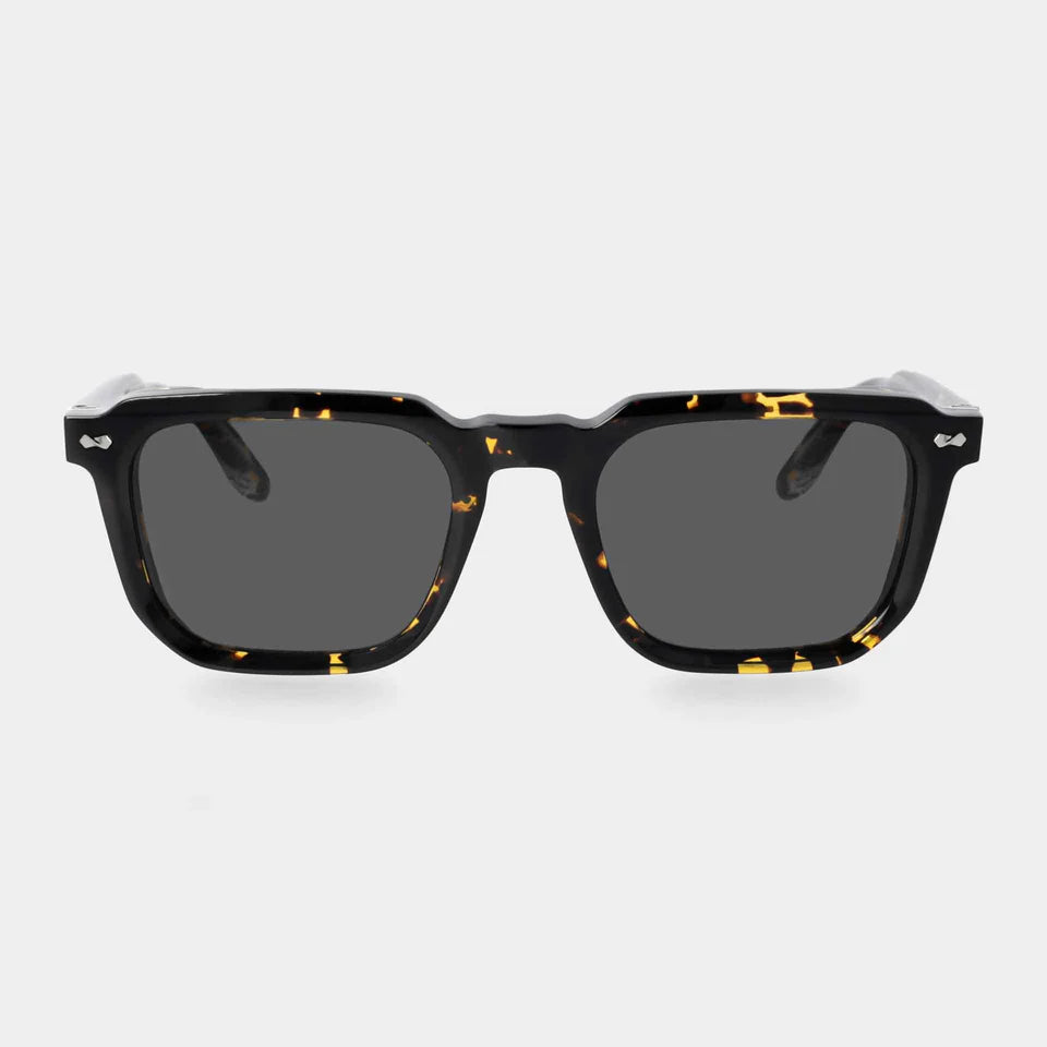 The Dart Eco Black Havana | Grey by TBD Eyewear are rectangular black and yellow tortoiseshell sunglasses with thick glossy acetate renew frames and dark lenses, viewed from the front on a light gray background. They offer 100% UV protection. , available at Richard Gelding Mayfair