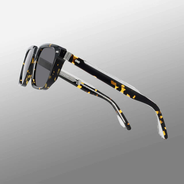 The Dart Eco Black Havana | Grey sunglasses by TBD Eyewear feature rectangular black havana frames in yellow tortoiseshell acetate renew and dark grey lenses offering 100% UV protection, set against a light-to-dark gray gradient background. , available at Richard Gelding Mayfair