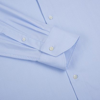 A close-up of the Canali Sky Blue Cotton Textured Shirt with thin white stripes, crisp fabric, white buttons, and a folded cuff showcasing its button closure—a stylish choice for casual or dress occasions. , available at Richard Gelding Mayfair