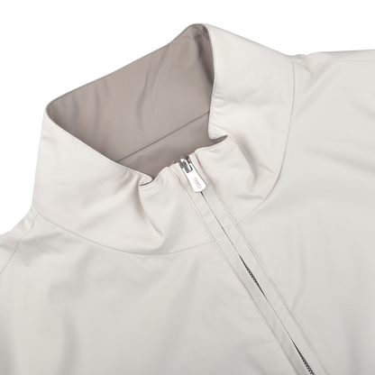 A close-up of the Fedeli Beige Nougat Nylon Reversible Blouson Jacket highlights its water-resistant material, high collar, and partially unzipped front. This regular fit piece balances style and functionality perfectly.