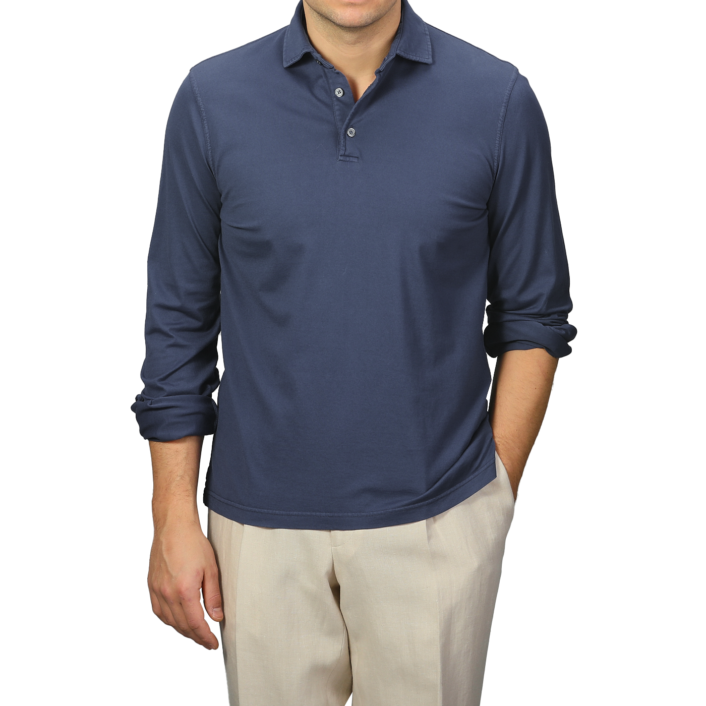 A person confidently stands against a neutral background, wearing a Fedeli Dark Blue Organic Cotton LS Polo Shirt with stylishly rolled navy long sleeves, paired with beige pants.