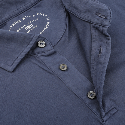 A close-up of the Fedeli Dark Blue Organic Cotton LS Polo Shirt showcases undone buttons, revealing a logo and text on the inside collar. Made from organic Giza cotton, this elegant long-sleeved polo offers sophistication and comfort.